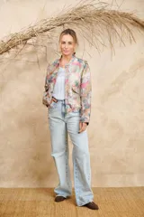Bomber estampada con motivos florales y de aves en tonos pastel, con cuello mao, cierre frontal con botones dorados, bolsillos laterales con solapa y puños elásticos.