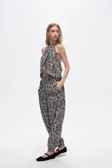 Pantalón slouchy de viscosa con estampado floral en tonos beige y negro, bolsillos laterales, cintura alta y detalle de punto smock en los tobillos.