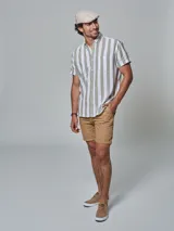 Bermuda color beige con cinturón, corte regular fit, dos bolsillos delanteros, dos traseros, un bolsillo relojero y botamanga con presilla. Aplique de badana.