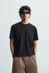 Camiseta blanca de algodón de peso medio, corte recto, cuello redondo y mangas cortas.