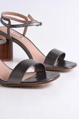 Sandalia de cuero color nude con pulsera al tobillo y taco cilíndrico de madera.