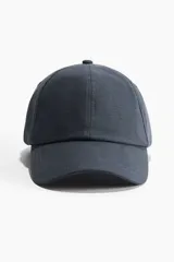 Gorra azul de lino y algodón con ojales bordados en la parte superior y trabilla ajustable con hebilla de metal atrás.