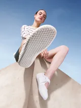 Zapatillas blancas de estilo barefoot, con suela fina, plana y flexible, sin tacos ni soporte rígido.