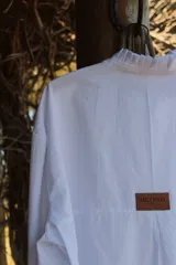 Camisa blanca de lino con cuello alto con volados y mangas largas.