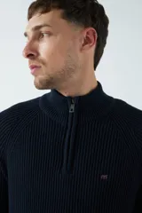 Sweater básico color beige de punto acanalado, con medio cierre frontal, cuello alto y logo bordado en el pecho.