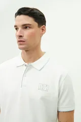 Polo color beige con textura, corte regular, logo estampado en el pecho y mangas cortas con ribete blanco.
