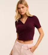 Blusa corta color borgoña, confeccionada en tejido de punto acanalado, con cuello polo y escote en V.
