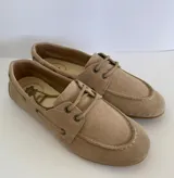Zapato náutico de gamuza color beige, con cordones y suela plana.