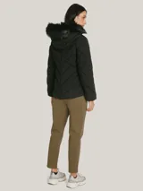 Campera acolchada negra de Tommy Hilfiger con cuello alto forrado en piel sintética, cierre de cremallera, bolsillos laterales y detalles distintivos de la marca.
