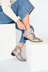 Botines de cuero vacuno con estampado de escamas en tonos neutros, caña baja y puntera ligeramente puntiaguda. Tacón bloque de 4 cm.