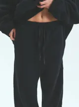 Pantalón de jogging negro de frisa esmerilada con cintura y botamanga elastizada, cordones de algodón con puntera termocontraíble y bolsillos laterales.