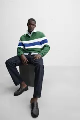 Polo de rugby verde con rayas horizontales azules y blancas, cuello blanco con solapa y cierre de botones, y mangas largas con puños acanalados.