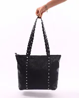 Bolso tote negro de cuero con tachas plateadas en las tiras. Tiene cierre superior, bolsillo interior y llavero.