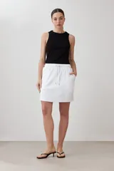 Minifalda blanca de corte recto, con pretina elastizada con cordón ajustable y bolsillos laterales.