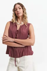Blusa sin mangas color beige con lazo frontal y textura liviana.