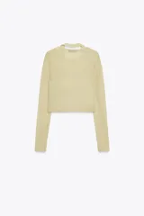 Top color crema de punto, con cuello redondo, manga larga y detalle de bajo superpuesto.