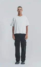 Pantalón cargo de pana negra, corte ancho y tiro alto con elástico en la cintura. Presenta bolsillos cargo amplios a los lados de las piernas, uno de ellos con un pequeño detalle de etiqueta o cierre.