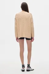 Sweater tejido color borgoña con cuello alto, corte oversize y mangas largas con detalle de trenzas verticales.