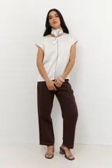 Blusa de manga 3/4 y cuello redondo, confeccionada en lino con acabado metalizado en tono beige o dorado claro.