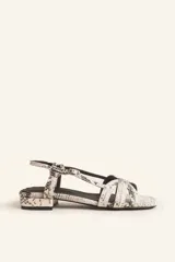 Sandalias bajas con estampado de piel de serpiente en tonos blanco y negro. Tiras finas entrecruzadas en el empeine, pulsera al tobillo con hebilla ajustable y pequeño tacón cuadrado.