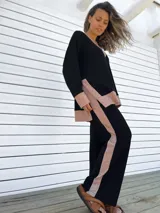 Conjunto de buzo y pantalón negro con detalles en color beige. El buzo es de corte holgado, con cuello en V y puños con ribete. El pantalón es de corte recto y tiro alto.