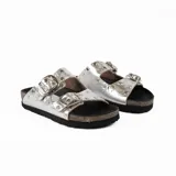 Sandalia plateada de cuero vacuno con forrería vacuna y detalle de tachas en la capellada. Tiene una plantilla birk forrada en cuero, y fondo negro de eva.