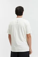 Remera color crema de corte recto y mangas cortas, con cuello redondo y estampa circular con texto en el frente.