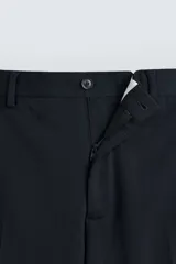 Pantalón de vestir gris oscuro, corte slim fit, confeccionado en tejido con 17% de lana. Cuenta con bolsillos frontales y traseros de vivo con botón. Cierre frontal con cremallera y botón.
