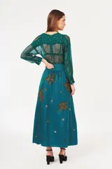 Falda larga color verde azulado con cintura alta y bordados dorados y plateados con forma de hojas.