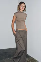 Top sin mangas, color marrón topo, con cuello alto y corte recto. Presenta un tejido de punto fino y mangas sisa con caída.