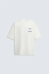 Camiseta blanca de corte holgado con cuello redondo y mangas cortas. Estampa en el pecho con la frase "Create a Narrative" en azul.