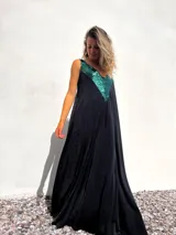 Vestido largo negro con escote en V y apliques de lentejuelas verdes en la parte superior.