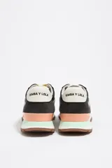 Zapatillas urbanas de diseño técnico que combinan paneles de serraje vacuno marrón con tejido blanco. Cuentan con empeine festoneado, estabilizador de talón en tono salmón con logo de la marca, detalle verde en el talón y suela de caucho dentada.