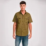 Camisa de manga corta color verde oliva con dos bolsillos de parche en el pecho con cierre de solapa y botón. Logo de Caterpillar bordado en la solapa del bolsillo izquierdo. Corte recto y cierre frontal con botones.