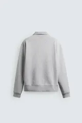 Sudadera color crema de corte recto, con cuello polo y cierre de cremallera metálica.