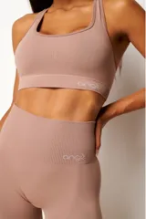 Top deportivo color rosa nude, con breteles anchos y espalda tipo nadador. Confeccionado con tecnología seamless y textura acanalada. Incluye forro y apertura para almohadillas.