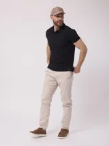 Chomba negra lisa de poliéster, algodón y core spun yarn, con cuello clásico y mangas cortas.