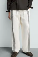 Pantalón de lino color crudo con rayas verticales negras, corte relaxed fit, cintura elástica ajustable con cordón, bolsillos laterales y traseros.