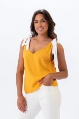 Musculosa mostaza de viscosa con breteles anchos y regulables con detalle de lazo en los hombros.