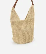 Bolso playero tipo tote bag confeccionado en paja color beige, con asas de mano de cuero sintético trenzado color marrón.