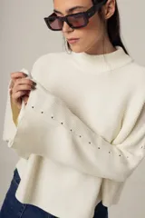 Sweater rojo de punto con cuello alto y mangas largas acampanadas.
