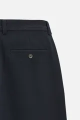 Pantalón slim fit negro confeccionado en tejido con elasticidad en ambas direcciones. Cuenta con bolsillos frontales y traseros de vivo con botón. Cierre frontal con cremallera y botón.