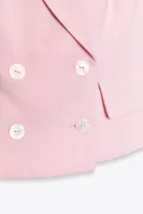Chaleco rosa con cuello halter y escote pico con solapa. Espalda descubierta. Bolsillos delanteros con solapa. Cierre frontal cruzado con botones.