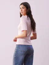 Remera rosa de tejido rib, con cuello redondo y manga corta.