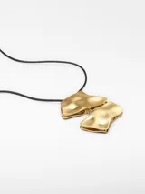 Collar con cordón negro ajustable y dije dorado con forma abstracta.
