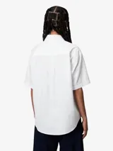 Camisa blanca de manga corta y corte holgado, confeccionada en popelina de algodón ligero. Luce la marca bordada en el pecho izquierdo.