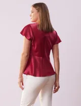 Blusa plateada de satén con manga corta amplia, corte bajo el busto y abertura con botón en la espalda.