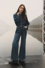 Pantalón de jean azul de corte acampanado, con tiro medio y cinco bolsillos.