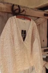 Camisa estampada con flores pequeñas, escote en V con detalle de puntilla, mangas largas abullonadas y cierre frontal con botones.