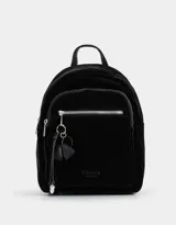 Mochila negra de cuerina con charm colgante, correas regulables, manija superior, cierre superior, bolsillo frontal con cierre y charm de metal, y bolsillos laterales.